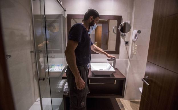 El encargado abre el grifo del baño de una habitación. Una vez cada siete días deben hacerlo con todos los grifos del hotel. 