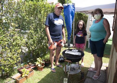 Imagen secundaria 1 - Izquierda: Pepe y Carmina, junto a su nieta Alicia, mientras preparan una barbacoa // .Fernando y Javier posan junto a su módulo del camping. 