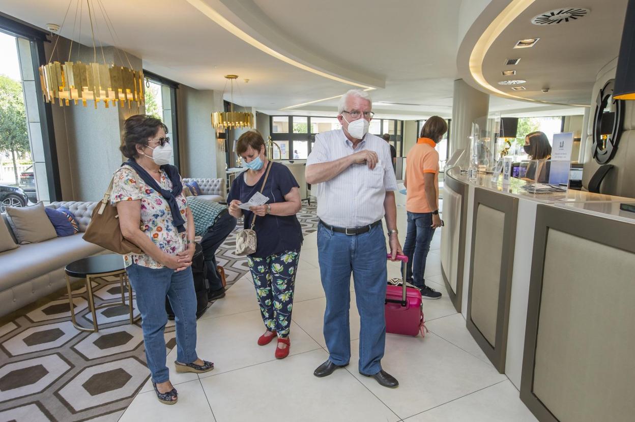 Varios visitantes llegan a la recepción del hotel Bahía, en Santander, donde se hospedarán durante los próximos días.