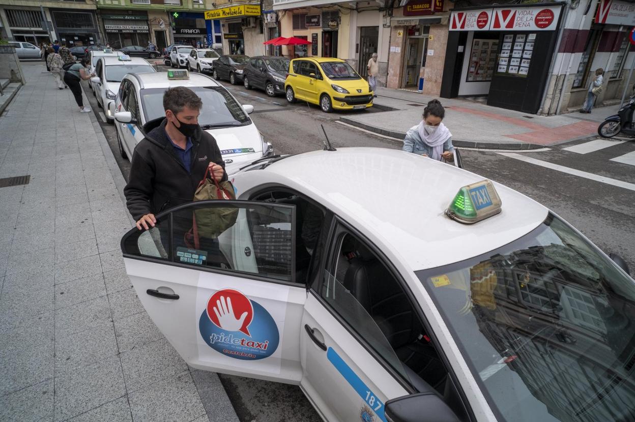 Una pareja se sube a un taxi en una parada de Santander. 