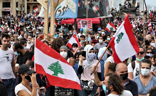 Manifestantes ondean banderas del Líbano en una manifestación de protestas tras la explosión del puerto de Beirut.