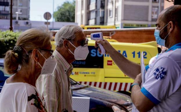 Un sanitario toma la temperatura a un hombre en el barrio madrileño de Villaverde.