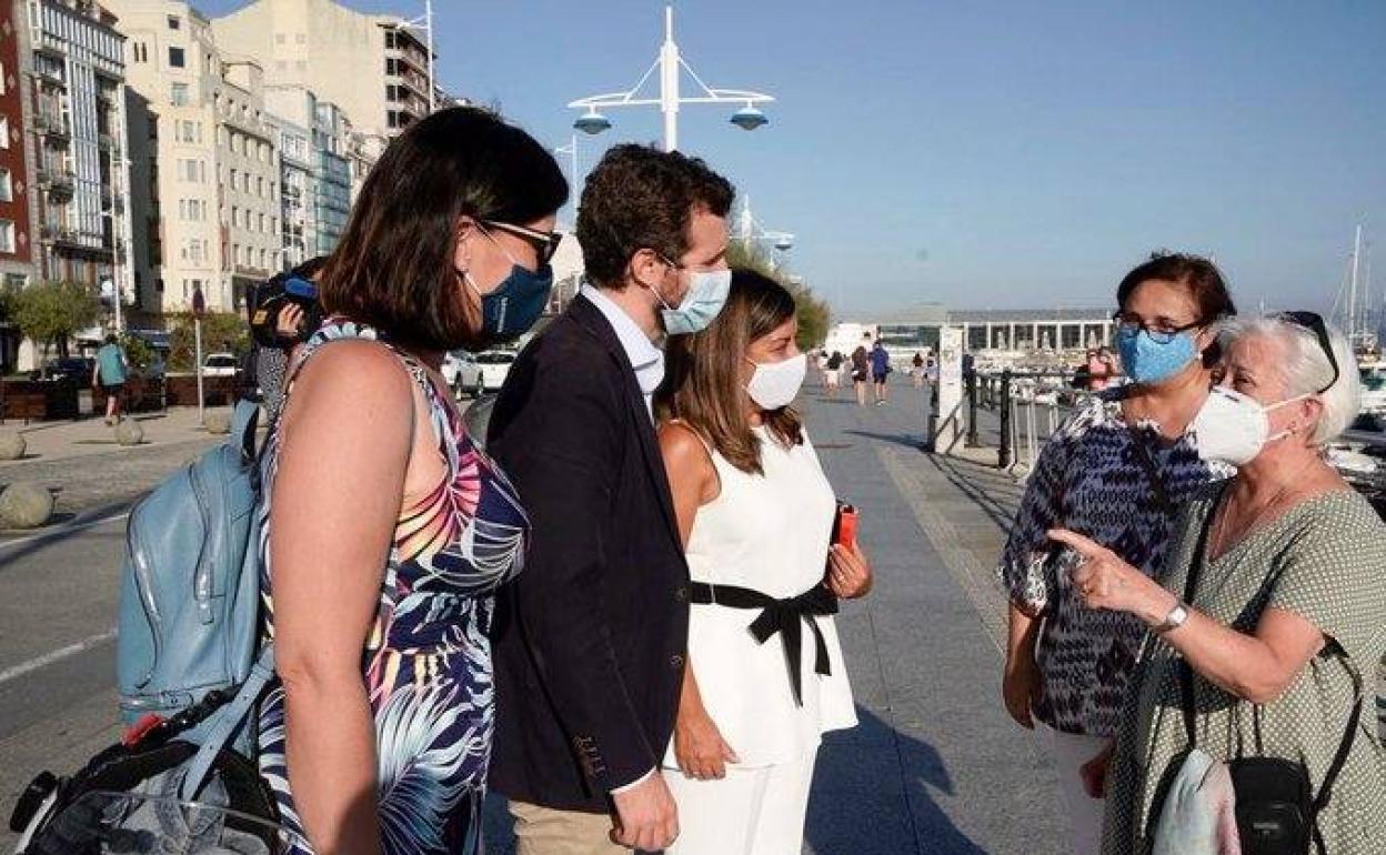 Gema Igual, pablo Casado y María José Sáenz de Buruaga departen con unas señoras en el paseo marítimo. 