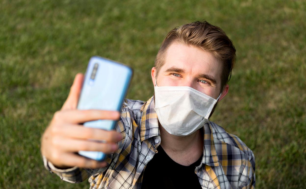 Un joven se realiza un 'selfie' con la mascarilla obligatoria.