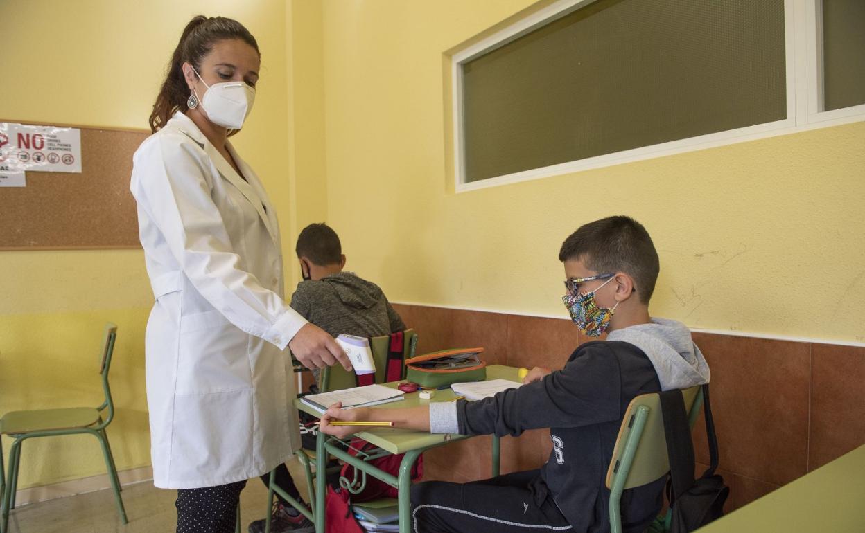 Una profesora toma la temperatura a un alumno. María Gil