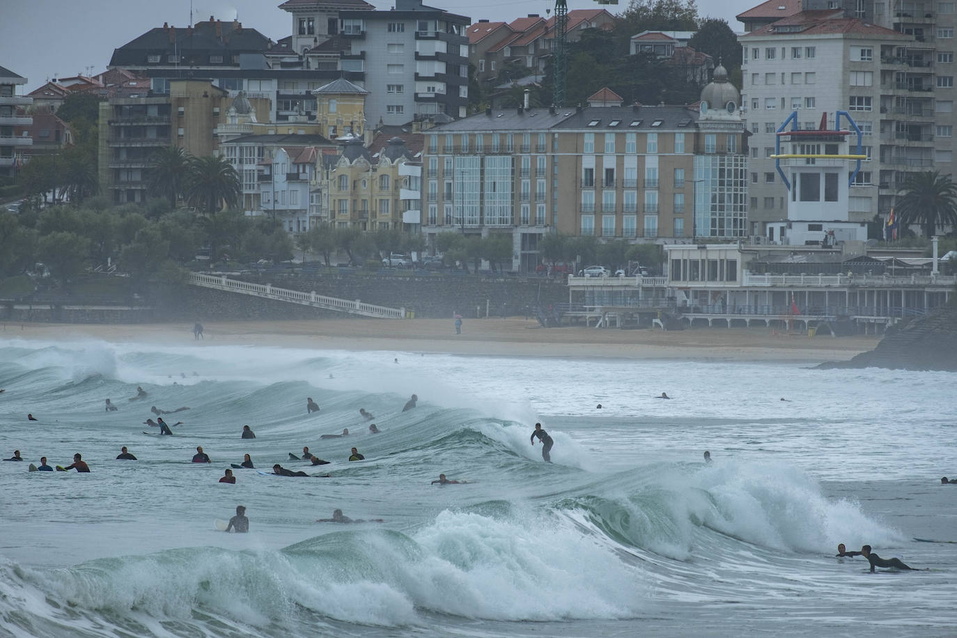 Llueve incesantemente en Cantabria y también hay grandes olas, que aprovechan los surfistas para pintar una de las estampas más habituales de Santander cuando el mar está embravecido.