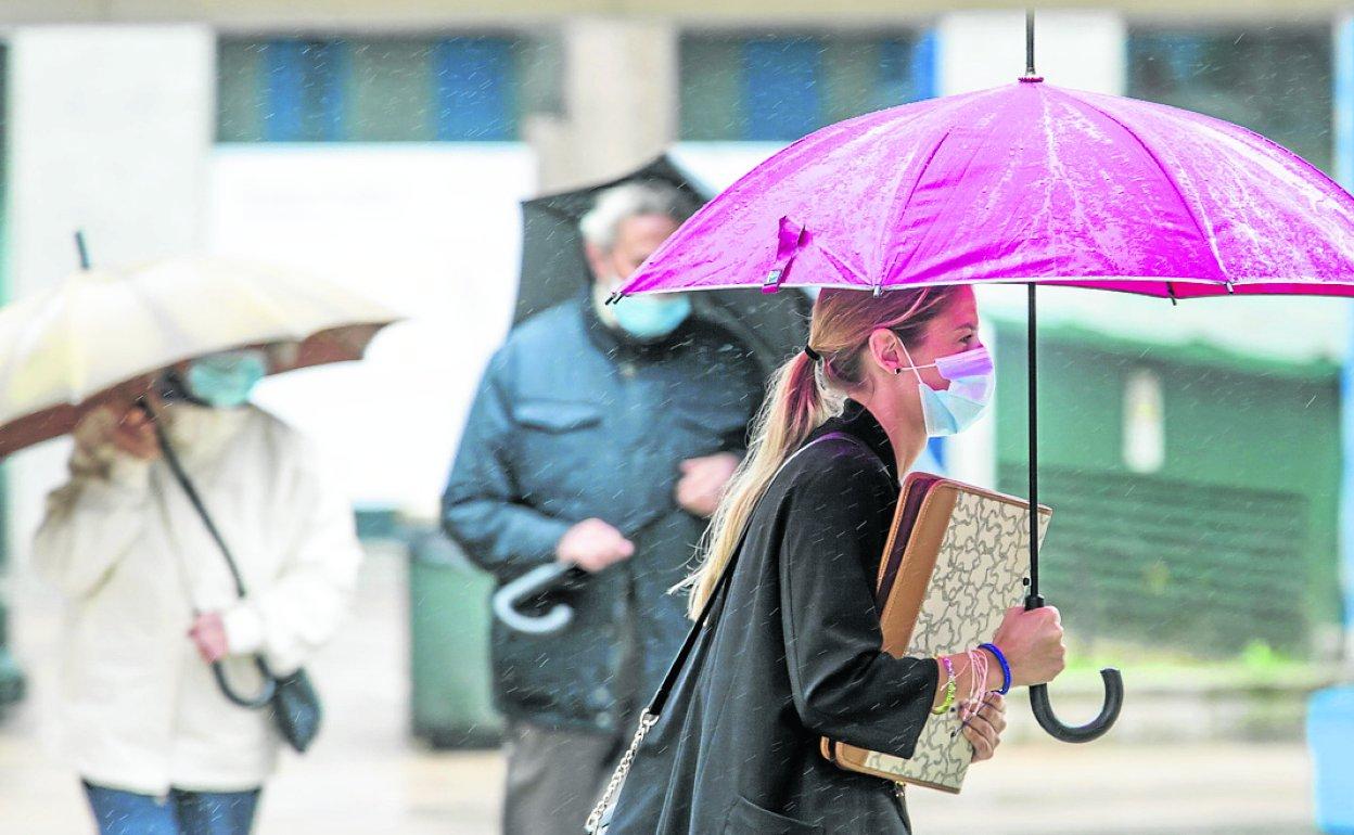 Una paseante se cubre de la lluvia en la Plaza Pombo de Santander. 