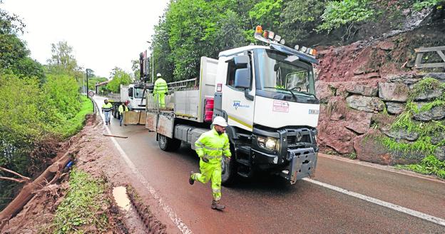 Trabajos para despejar la vía. Varios operarios trabajan en la carretera autonómica CA-182, en el municipio de Mazcuerras, tratando de retirar el argayo de tierra y barro que ocupó la vía, que permaneció cerrada al tráfico durante diez horas. La tierra arrastró un árbol que rompió las escolleras del río Saja. 