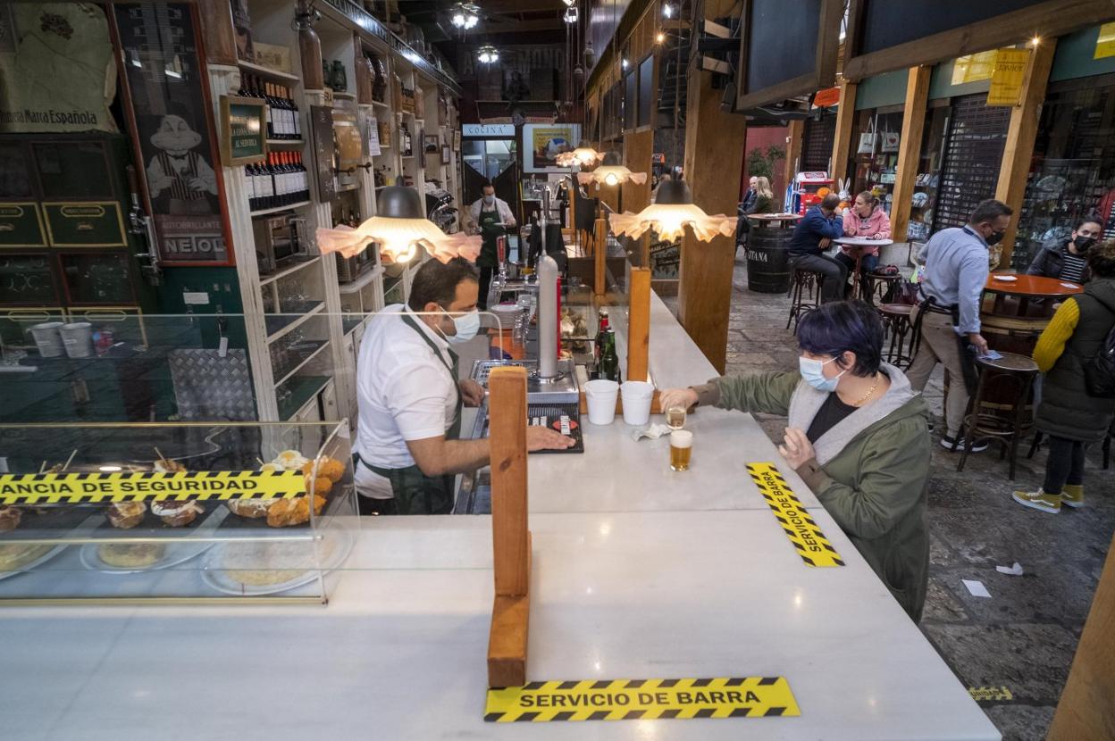  Una clienta se acerca a la barra sólo para pagar, pues no se puede usar para consumir, mientras que en el resto del establecimiento el aforo se reduce un 30%.