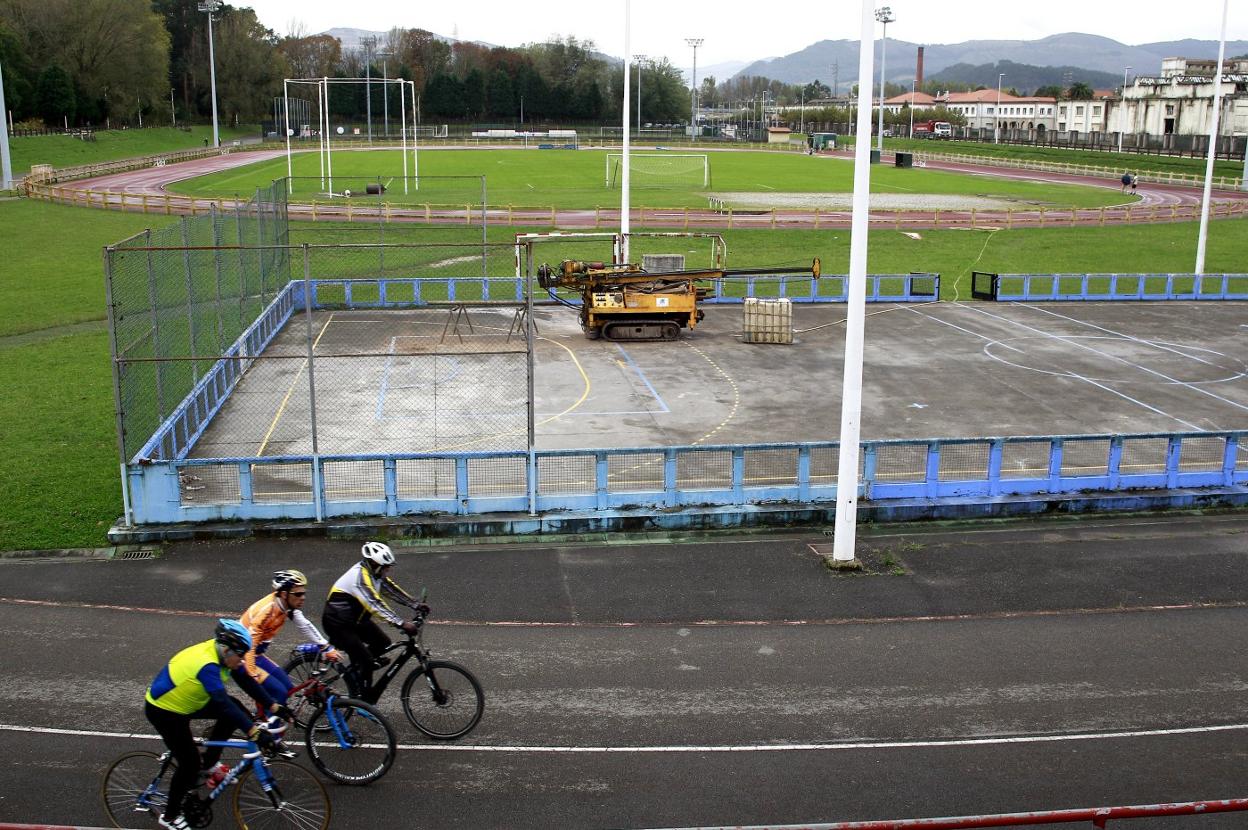 Un grupo de ciclistas pasa junto a la zona en la que se levantará el módulo de la escuela de atletismo. 