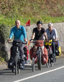 Imagen secundaria 2 - Arriba, la A-8, a su paso por Maliaño, con menos tráfico. Abajo, la confitería Pindal en Unquera y tres ciclistas extranjeros que están haciendo el Camino de Santiago. 