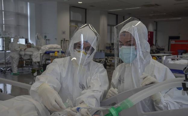 Dos profesionales, con los buzos de protección, atienden a un paciente covid ingresado en UCI. 