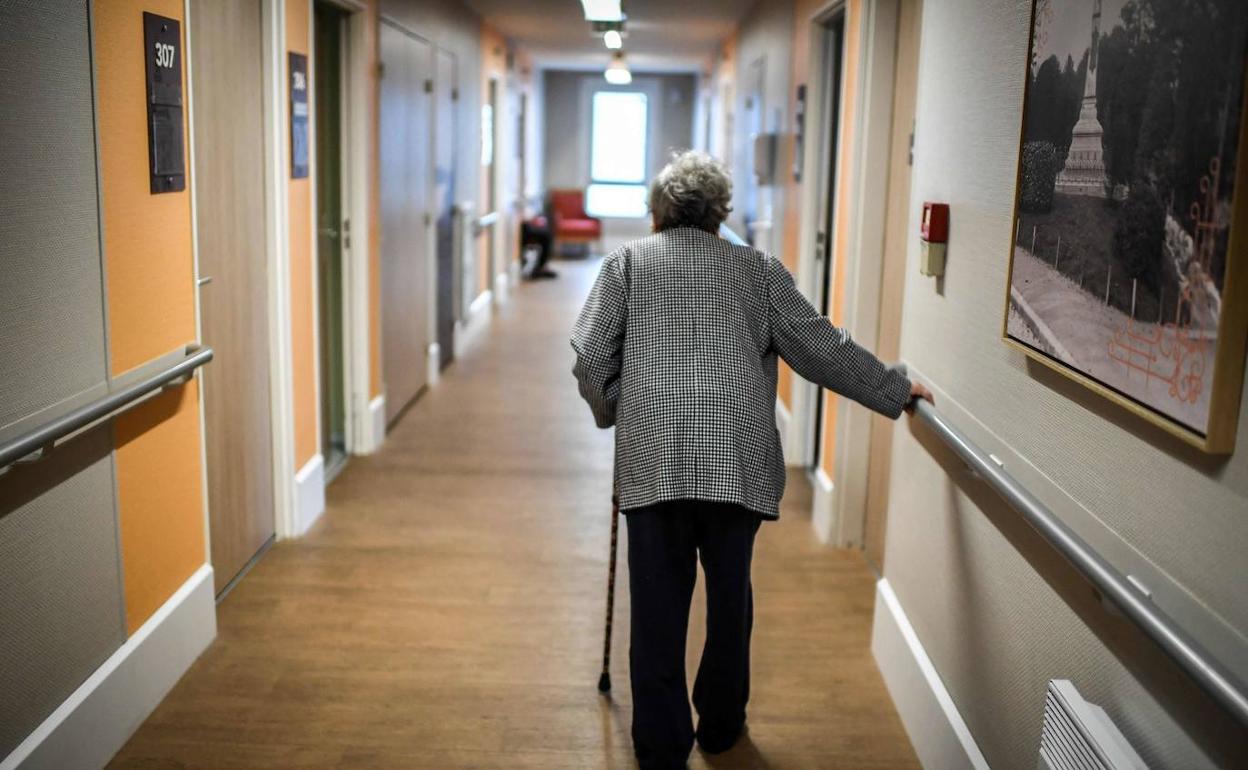 Una mujer pasea por el interior de una residencia para personas mayores.