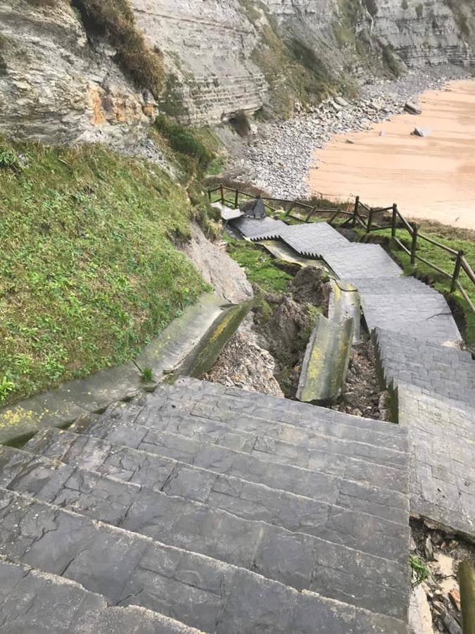 La escalera de acceso a la playa pequeña de Langre se ha fraccionado al desprenderse la pared de rocas que le daban sostén a causa de las intensas lluvias.