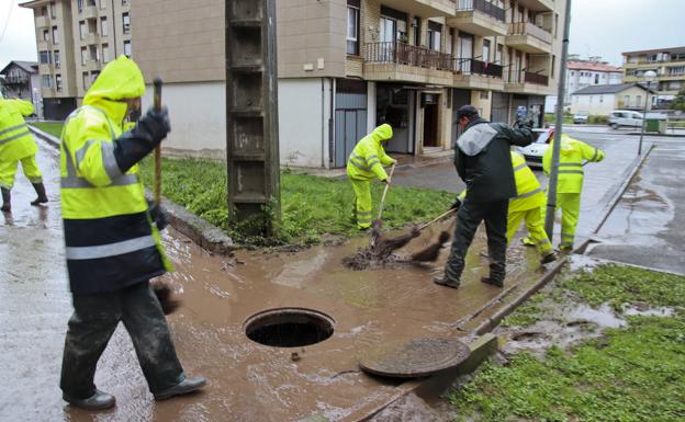 Los operarios de limpieza tratan de retirar el agua acumulada tras los chaparrones en el barrio Pelegrín de Laredo.