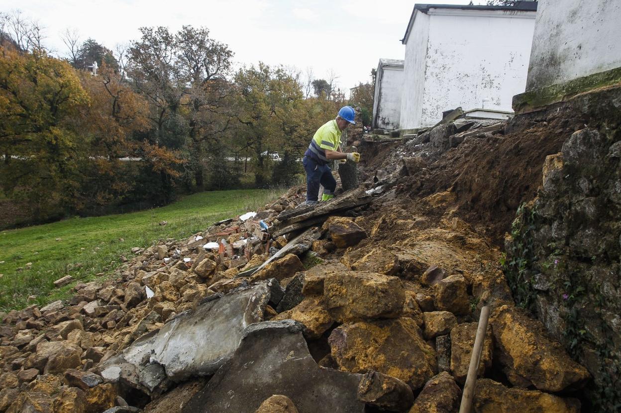 Un operario trabaja en la reparación del muro caído en el cementerio de Geloria. 