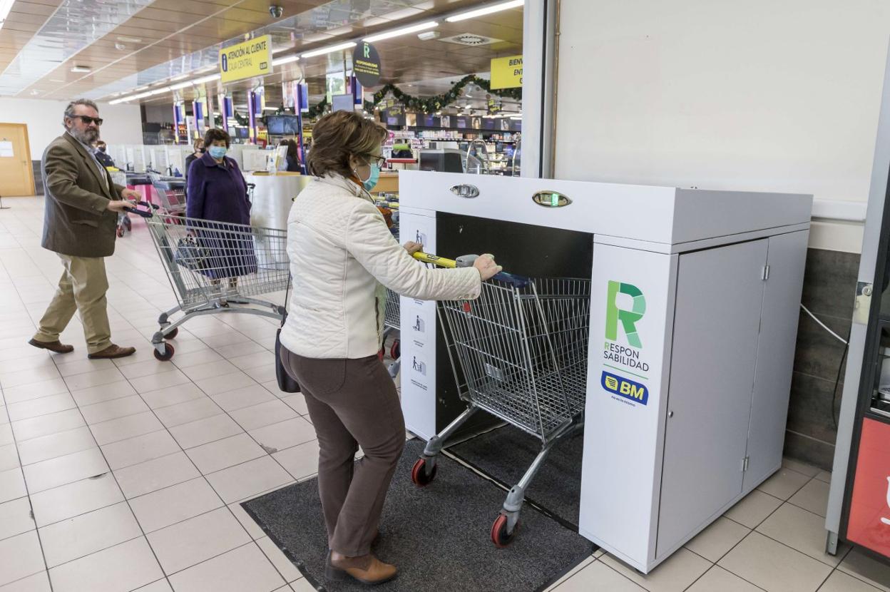 Una cliente utiliza la primera máquina para la desinfección del carro de la compra en el supermercado BM de la S-20.