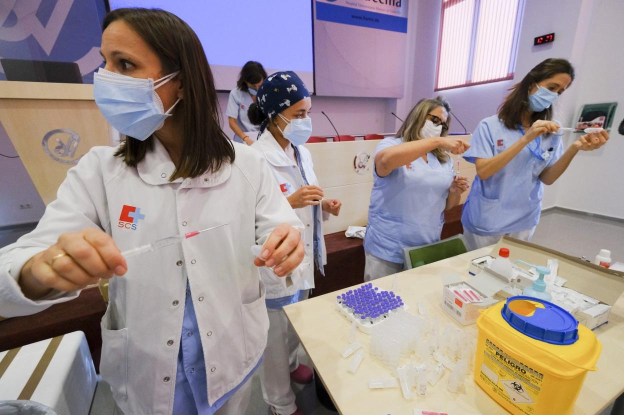 Varias enfermeras preparan las vacunas en el salón de actos de Valdecilla, antes de proceder a la administración de las dosis a sus compañeros. 