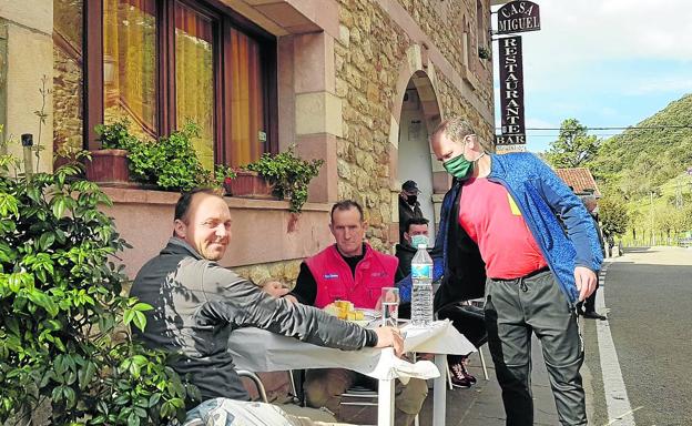 Jorge Vega sirve el menú a dos obreros de la construcción en la terraza de Casa Miguel.