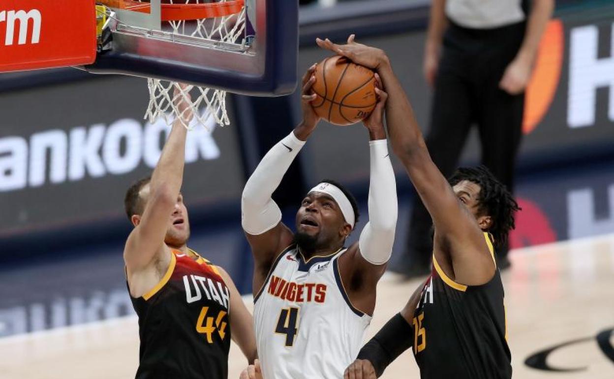 Paul Millsap, de los Denver Nuggets, es bloqueado por Bojan Bogdanovic y Derrick Favors del Utah Jazz 