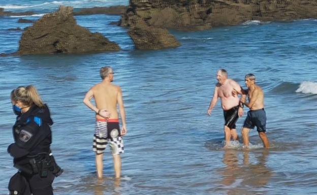 Momento en el que hombre consigue salir del agua por su propio pie, con la ayuda de uno de los testigos que acudieron en su ayuda.