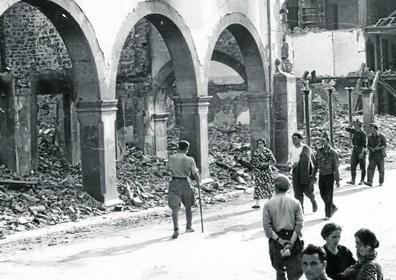 Imagen secundaria 1 - Arriba: La Plaza y entrada a la calle Cántabra.. Abajo: Vecinos y soldados pasan junto a las ruinas de la Plaza y Grupo de personas durante una comida en Casa Susa.