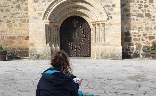 Imagen. Lucía sentada frente a la Puerta del Perdón del Monasterio de Santo Toribio.