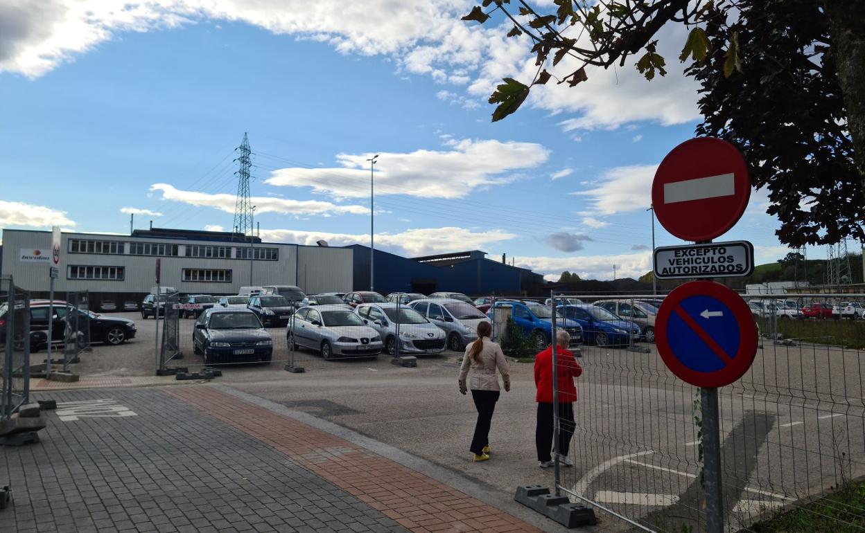 Dos residentes caminan junto al aparcamiento de La Vidriera, este invierno, a las afueras del casco urbano de Maliaño-Muriedas.