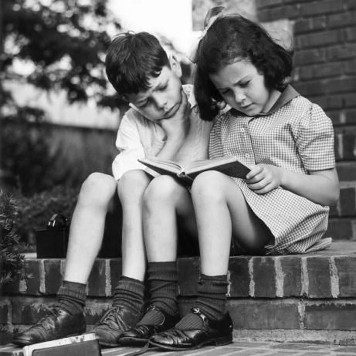 Dos pequeños hojean un libro.