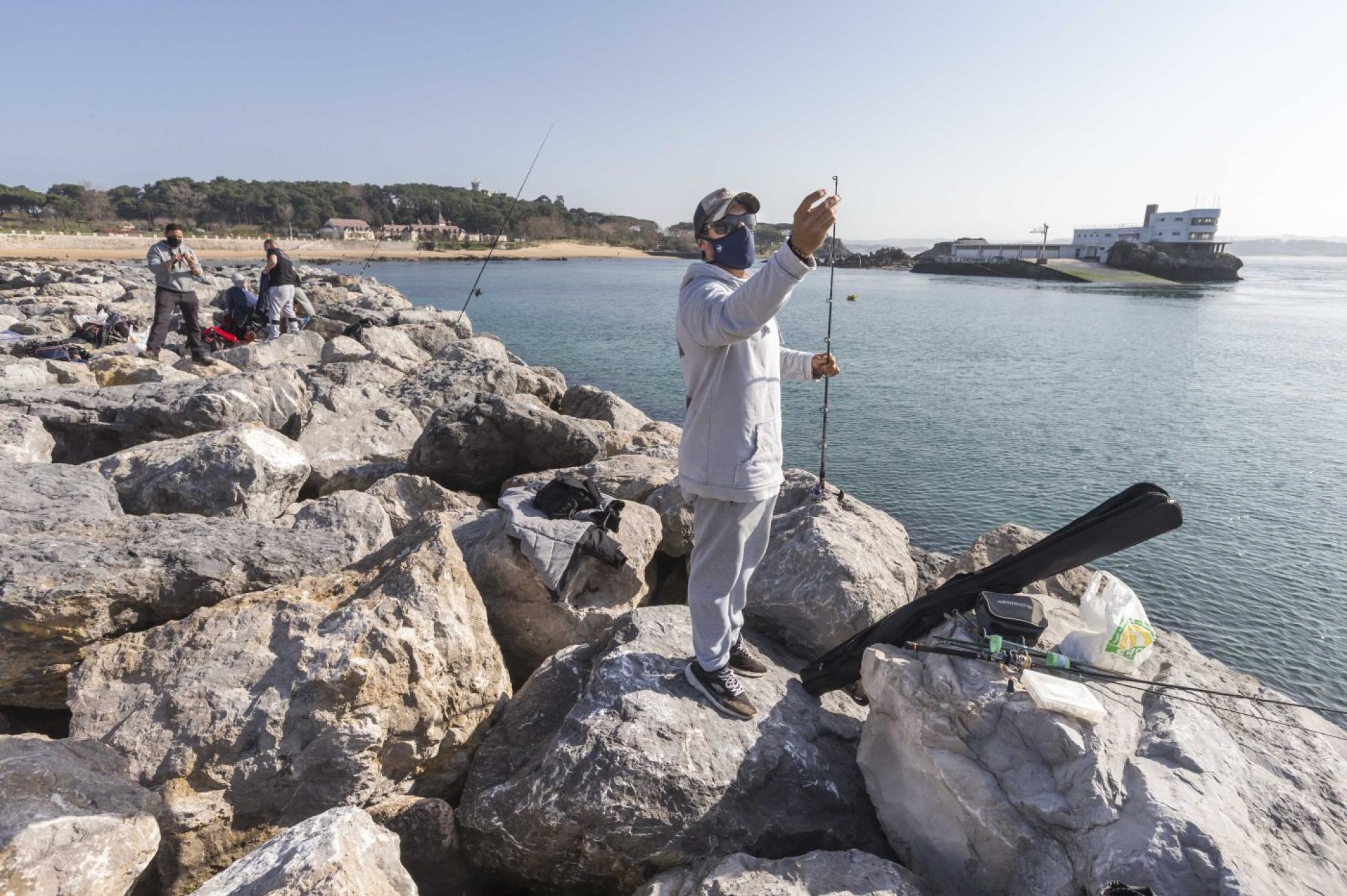 Un pescador prepara su caña para lanzarla desde el espigón de La Magdalena.