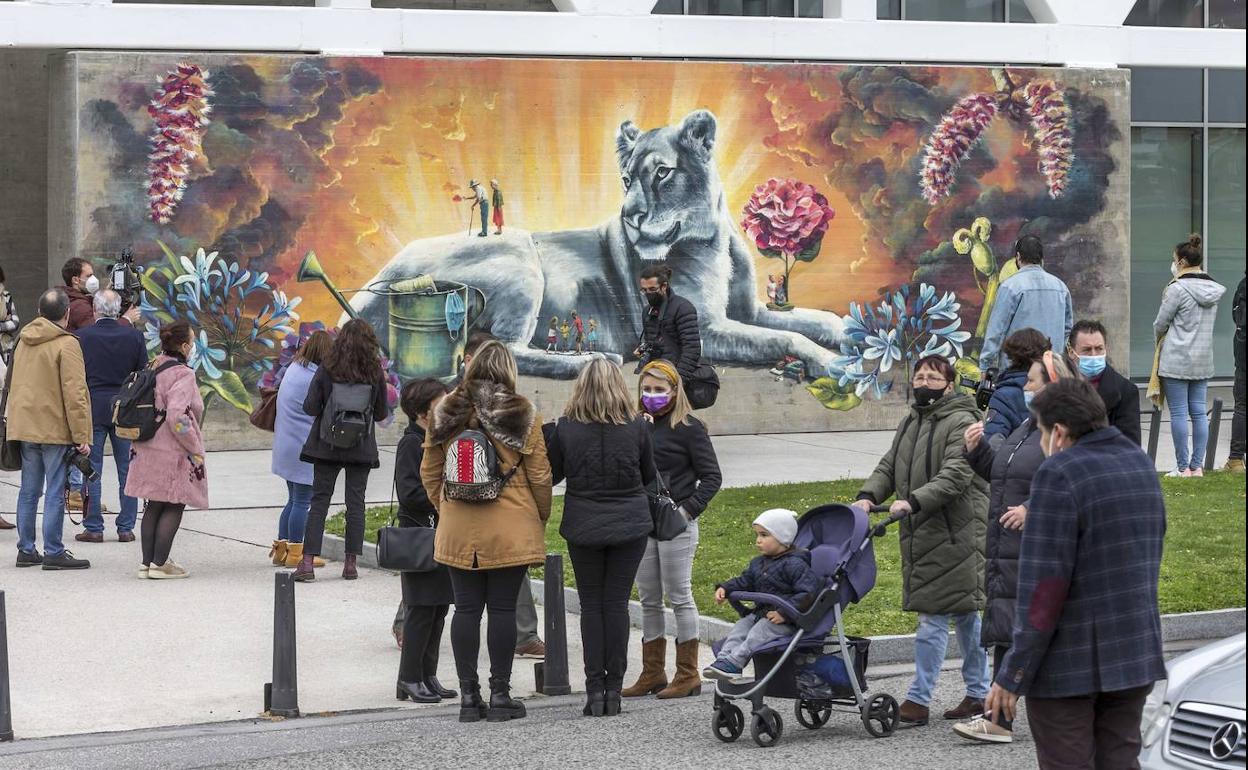 Gente paseando frente al mural del Icass, un homaneja a los profesionales de la dependencia durante la pandemia.