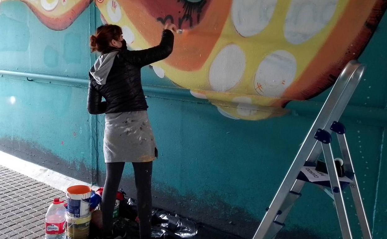 La artista Marina Casaos restaurando uno de sus murales, sobre la vida submarina, que ha sido dañado por los grafiteros cogidos 'in fraganti'