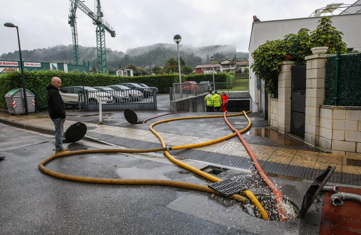 Trabajos de achique de agua en el garaje de una de las viviendas afectadas por las inundaciones en Duález. 