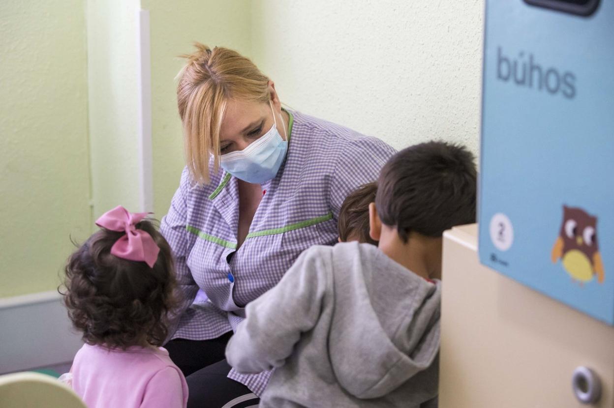 Una trabajadora de una guardería, junto a menores de tres años sin mascarilla. 