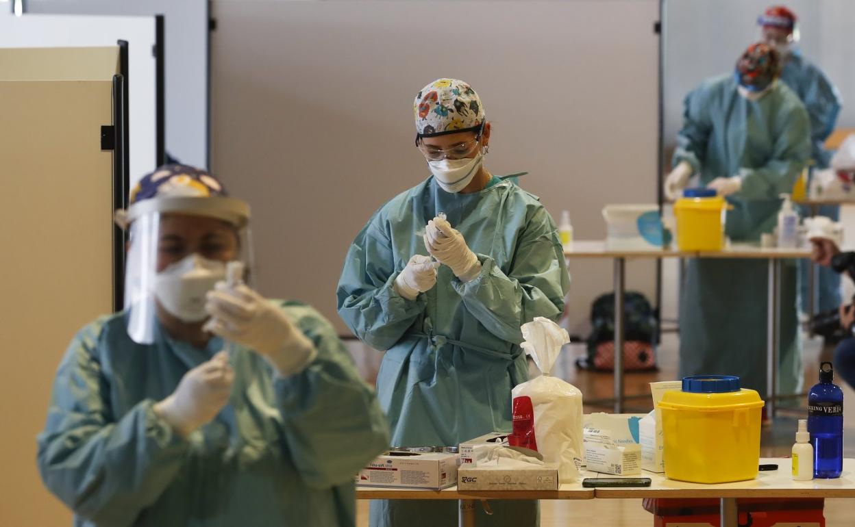 Varias profesionales preparan las dosis en el inicio de la vacunación en el Palacio de Exposiciones de Santander.