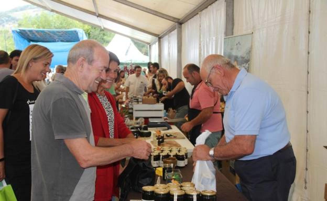 Una familia compra miel de Liébana con DOP en la feria de la miel en Vega de Liébana