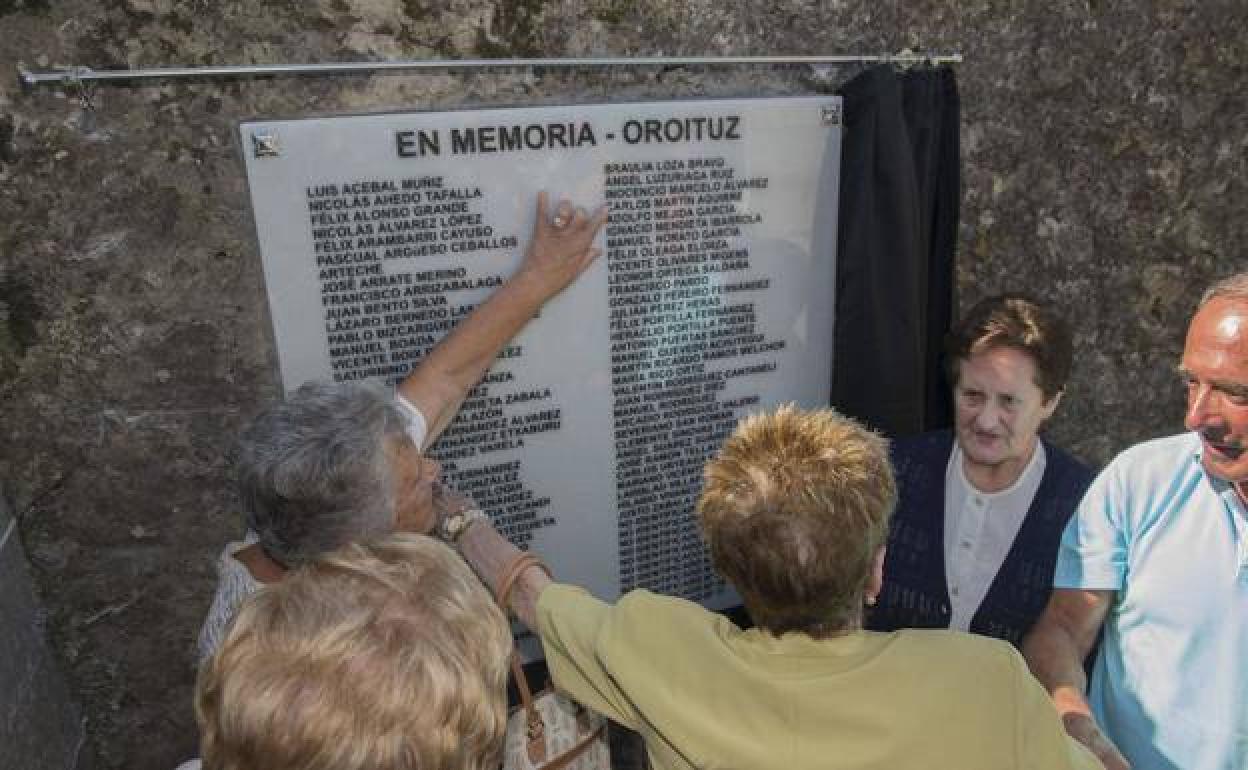 Vecinos de Limpias junto a una lista de nombres en memoria de los republicanos en el cementerio de la localidad