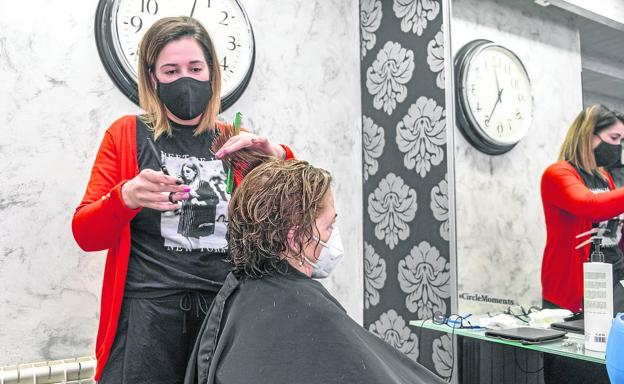 Yolanda Sánchez corta el pelo a una clienta en su peluquería de la calle Los Ciruelos de Santander. 