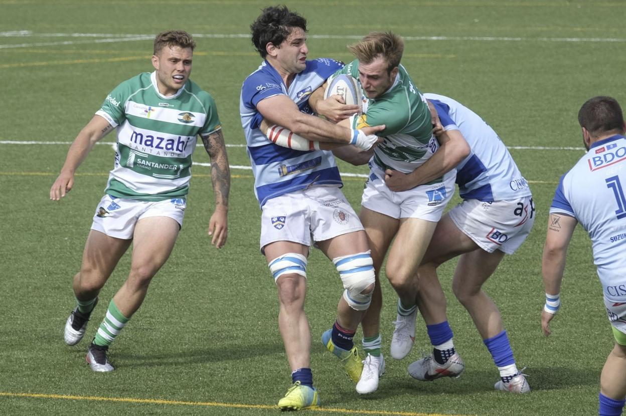 Finlay Sharp es placado por dos jugadores del Cisneros en el partido del sábado en San Román.