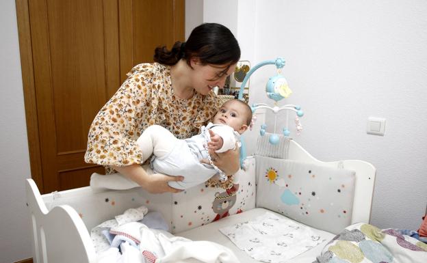 Laura Piñero, en su casa de Castañeda, pone en la cuna a su hijo Luis, de siete meses.