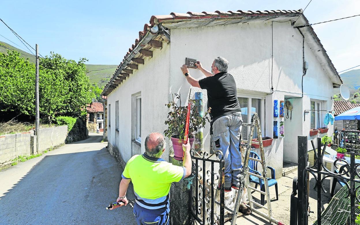 Operarios municipales fijan una placa en una vivienda del pueblo de Viaña. 