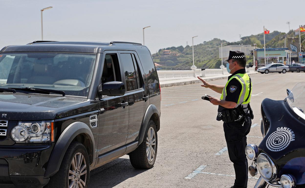 Un agente de la policía local realiza un control en el aparcamiento de la playa de Comillas. 