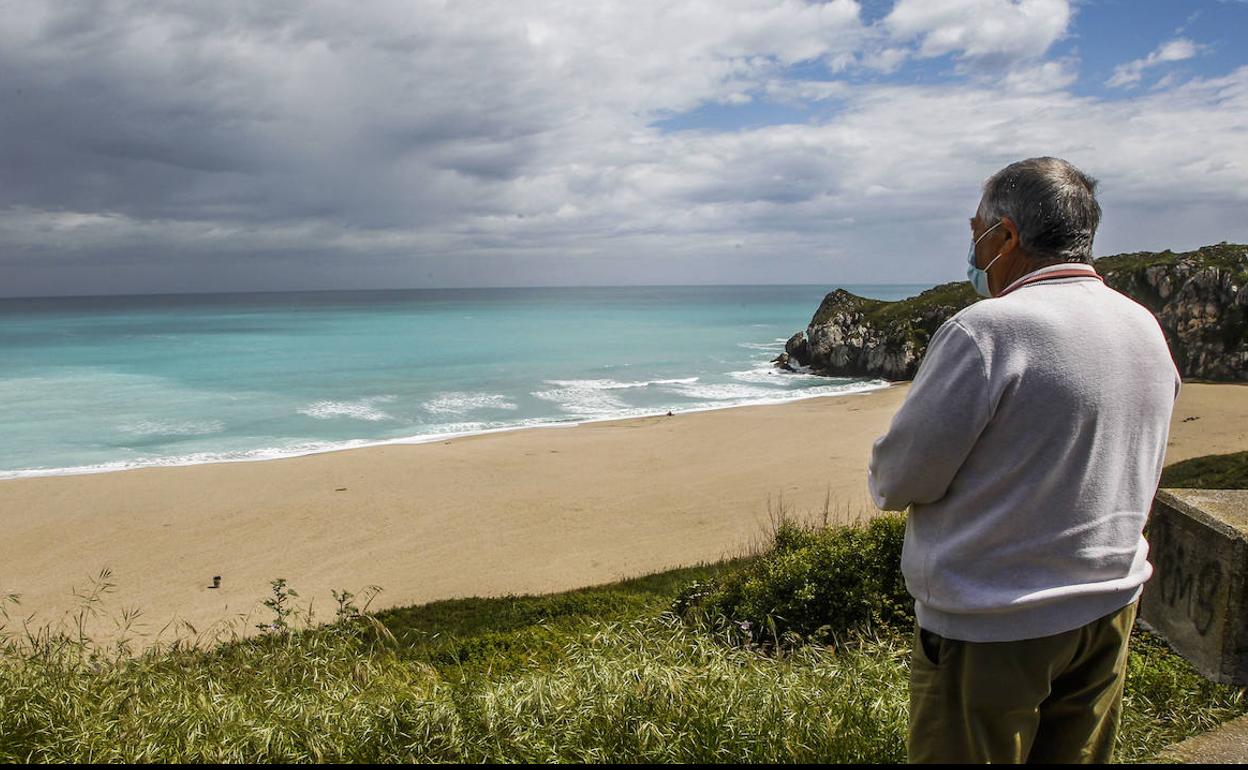 Un vecino de Miengo observa, ayer, en la playa de Usgo, la tonalidad azul turquesa del agua.