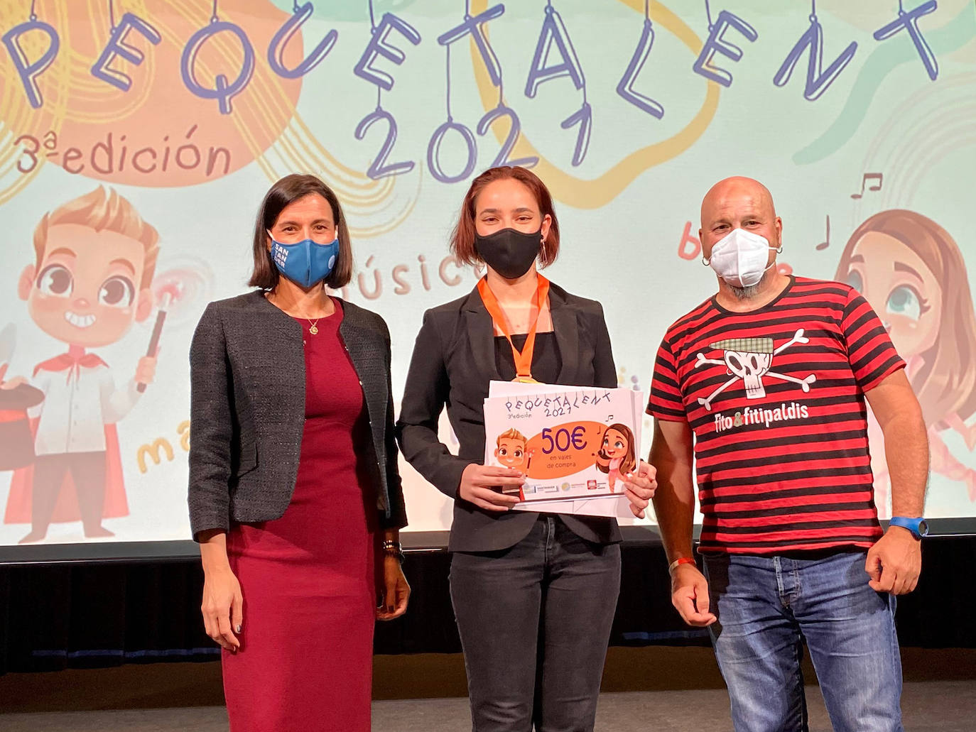 Sara Cimiano (Santander, 16 años), con sus premios, en compañía de Gema Igual y el músico tradicional Miguel Cadavieco. Fue una de las cuatro menciones especiales por cantar ‘La Despedida’, de Cami, aunque en la gala optó por interpretar un tema de Belén Aguilera, 'Mía'. Se llevó una medalla y vale de 50 euros para consumir en el comercio.