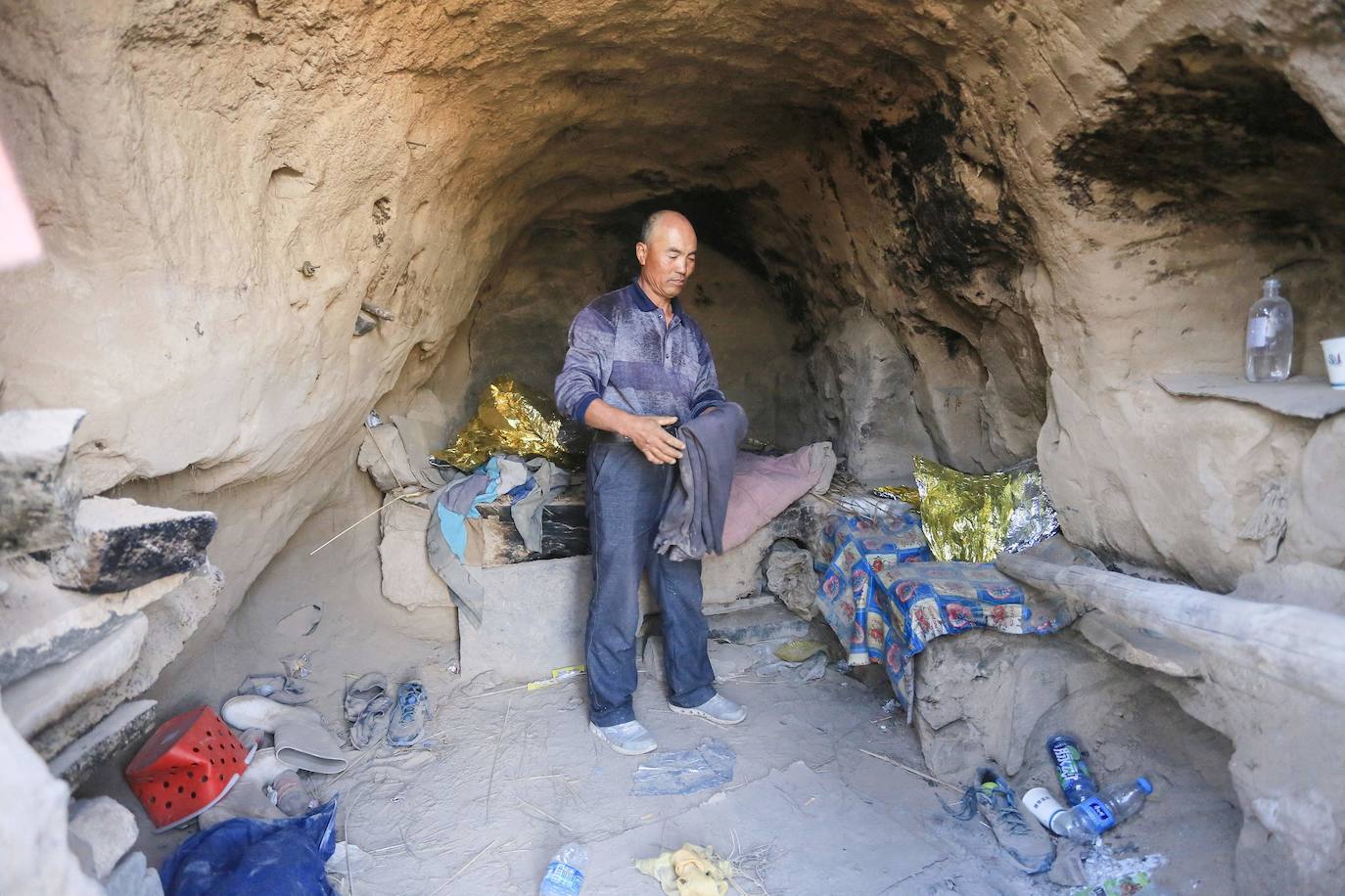 El pastor Zhu Keming, aclamado como un héroe en China por rescatar a seis corredores, muestra la vivienda-cueva donde refugió a los atletas afectados cerca de la ciudad de Baiyin.