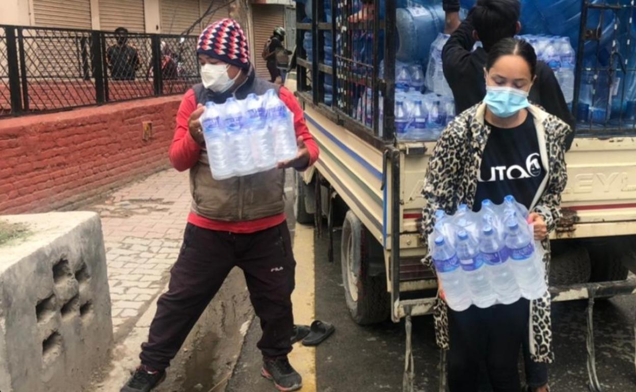 Dos voluntarios reparten agua en las calles de Katmandú. 