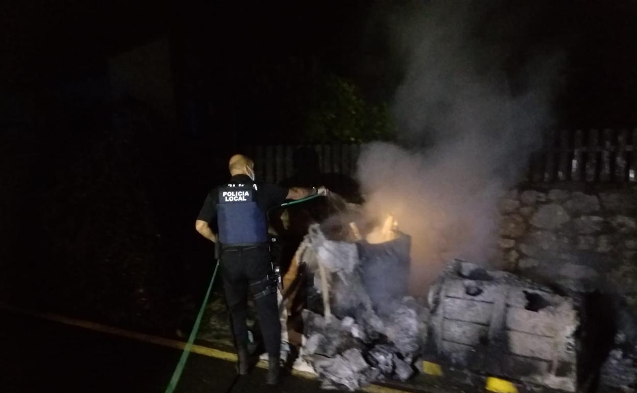 Policía Local de Noja sofocando las llamas de los contenedores quemados por los jóvenes.