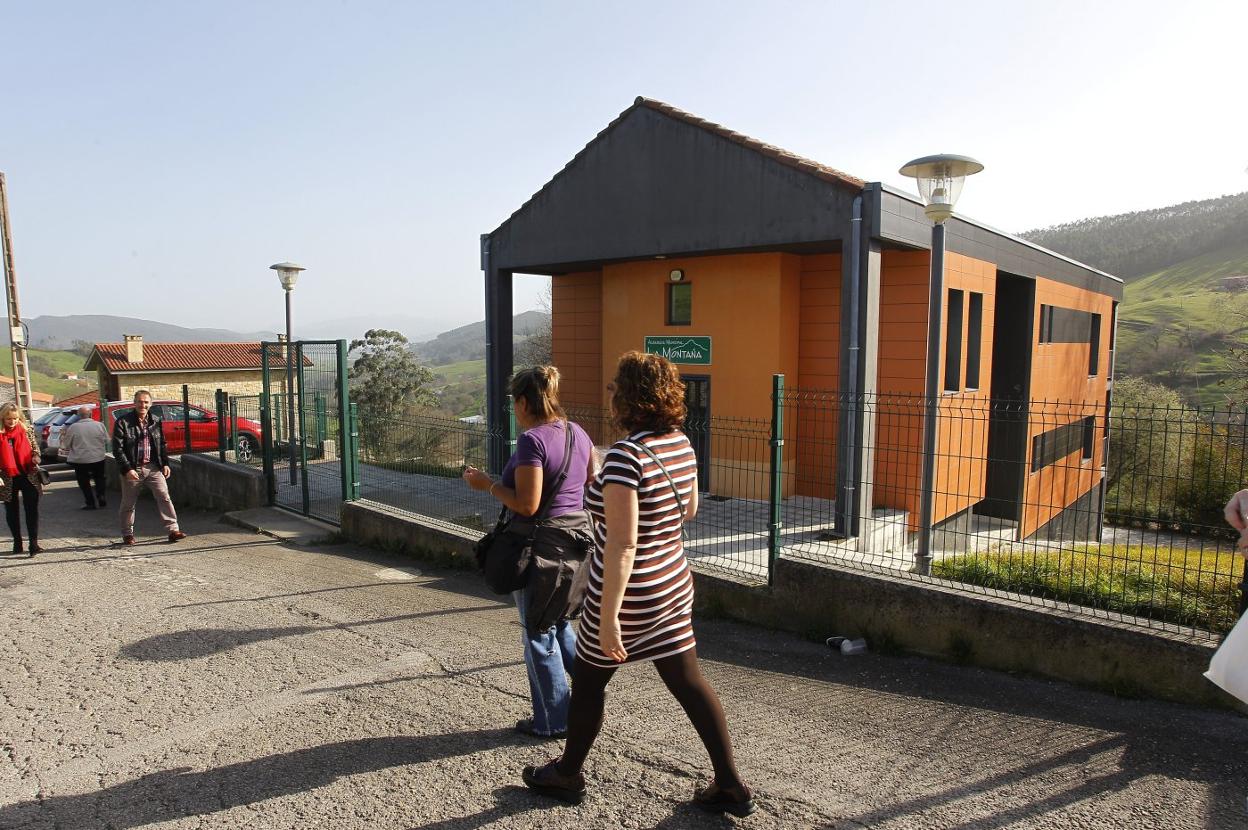 Varios vecinos pasan junto al albergue juvenil de La Montaña, antiguas escuelas de la localidad. 