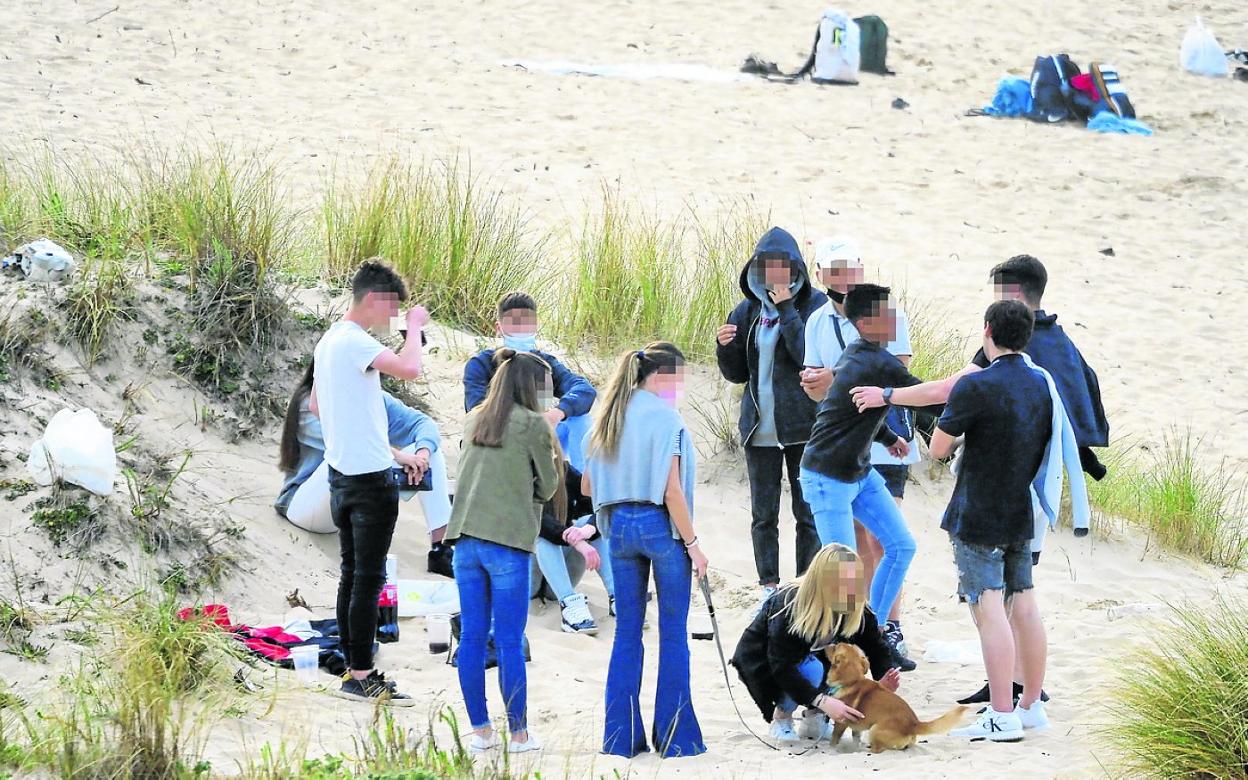 Un grupo de jóvenes, de botellón en una playa. sane