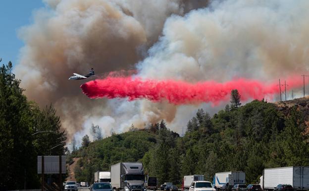 Un avión trata de sofocar un incendio junto a una transitada autopista en California, cerca de la ciudad de Shasta Lake.